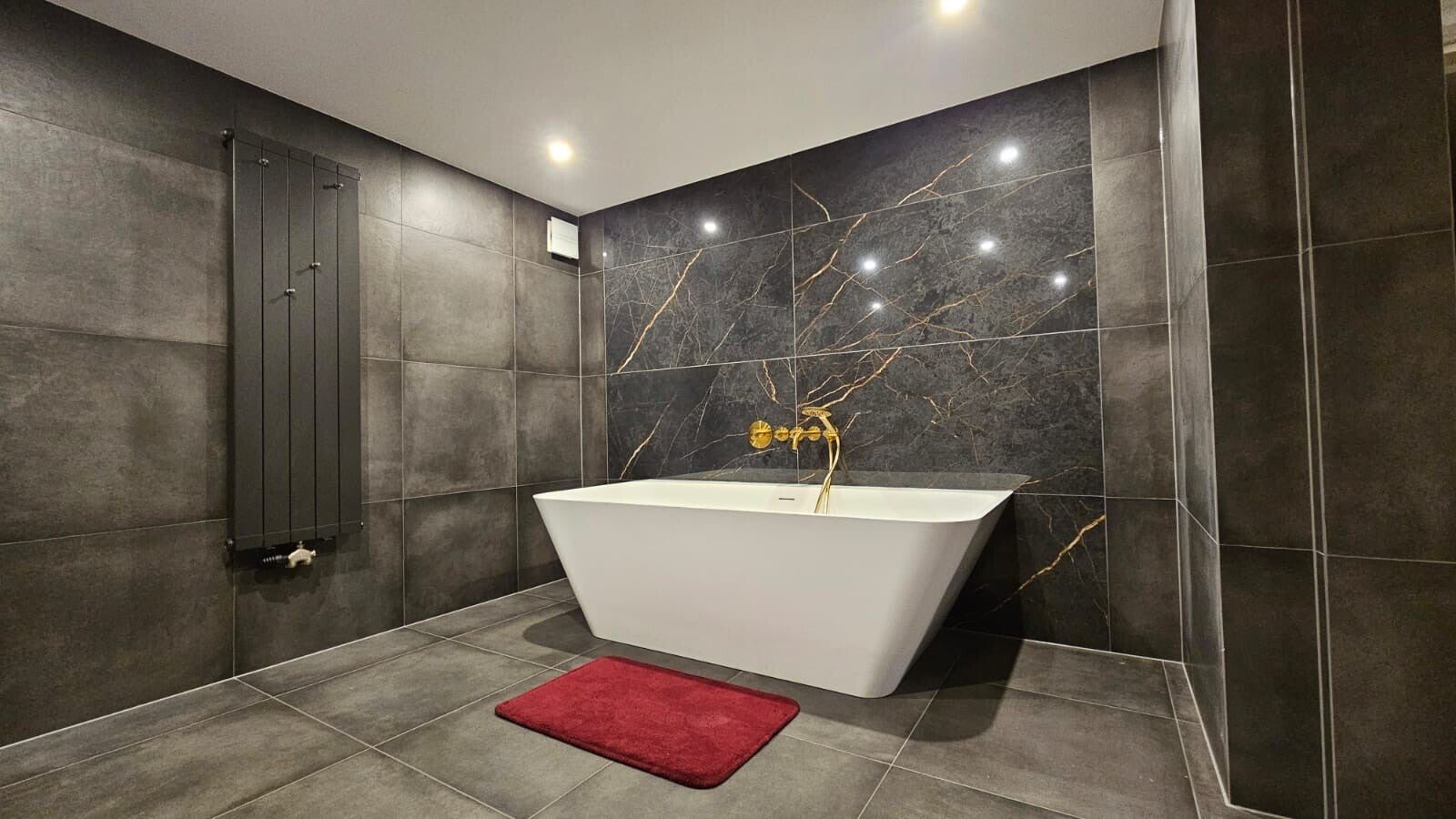 Luxe badkamer met marmerlook wandtegels, gouden kranen en vrijstaand bad